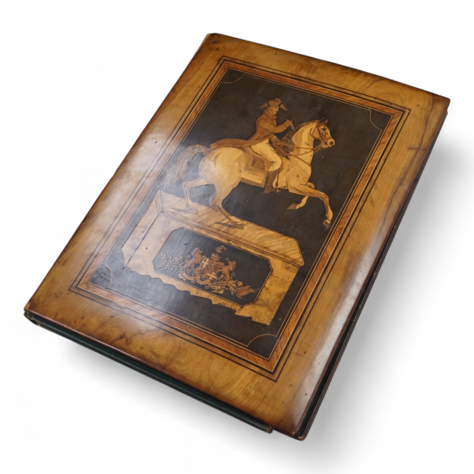 An olive and marquetry desk blotter, Duke of Wellington on horseback and his coat of arms, together with a cloth and gilt book, Army and Navy Drolleries by Captain Seccombe